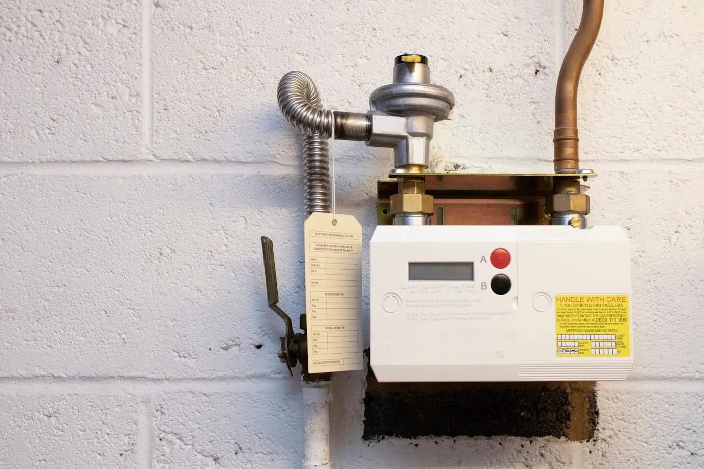 A domestic gas meter and its pipework mounted on a wall